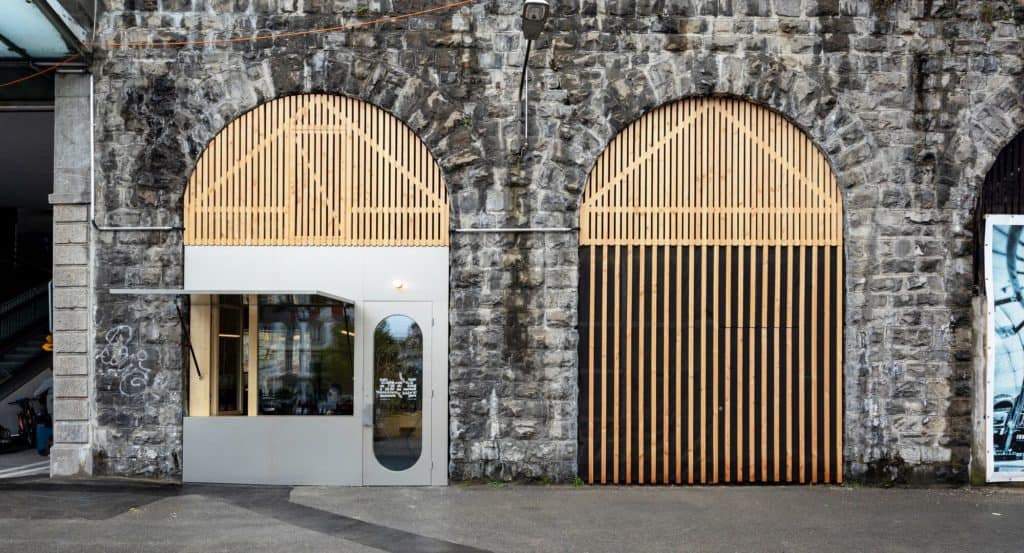 Façade moderne avec arches en pierre et portes en bois design.