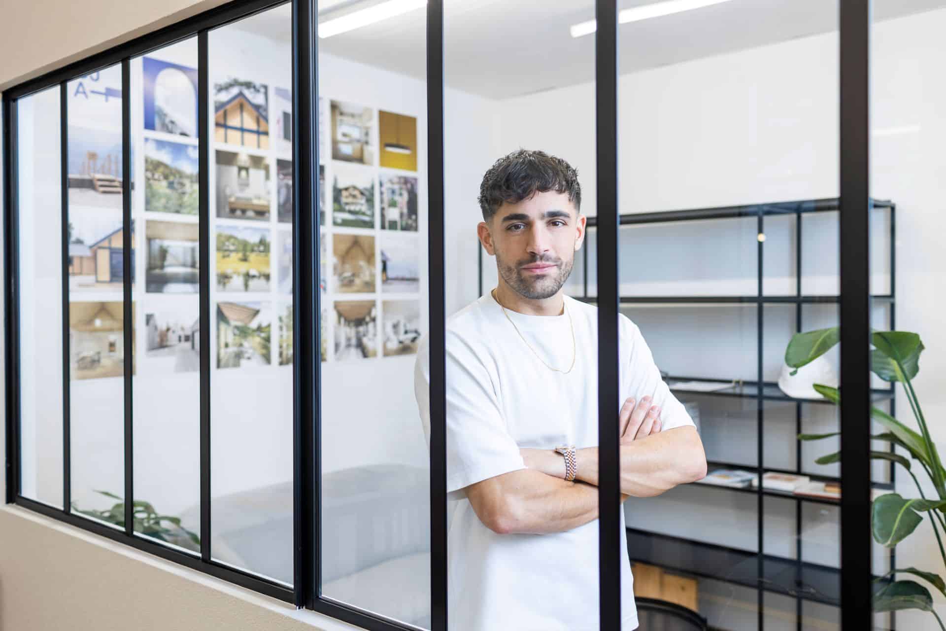 Jeune homme dans un bureau moderne avec vue sur des plans et des photos d'architecture.