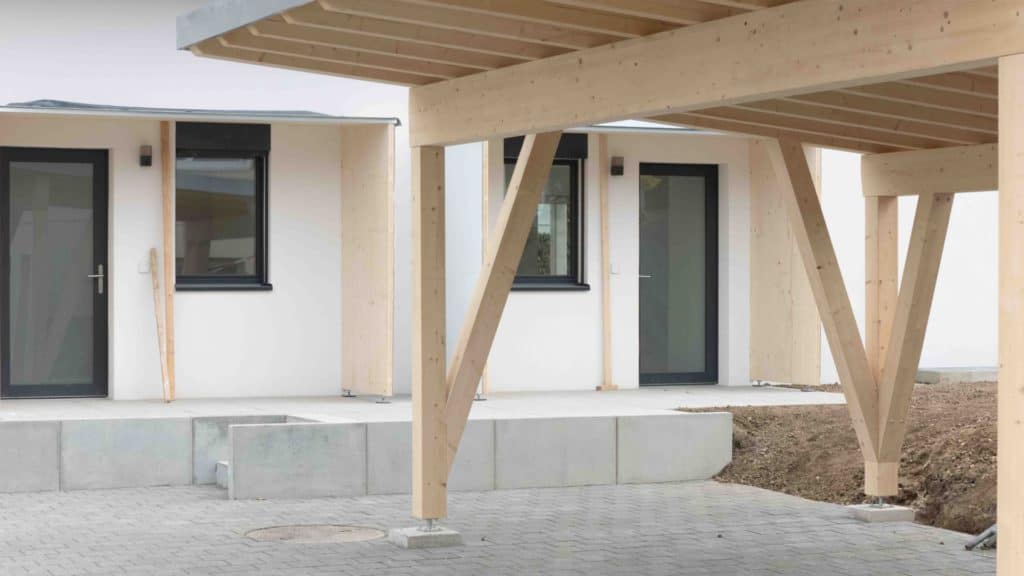 Maison moderne avec terrasse en bois et fenêtres noires à Lavigny.